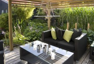 Modern outdoor living in a backyard, with beautiful plants and a wicker sofa and table.