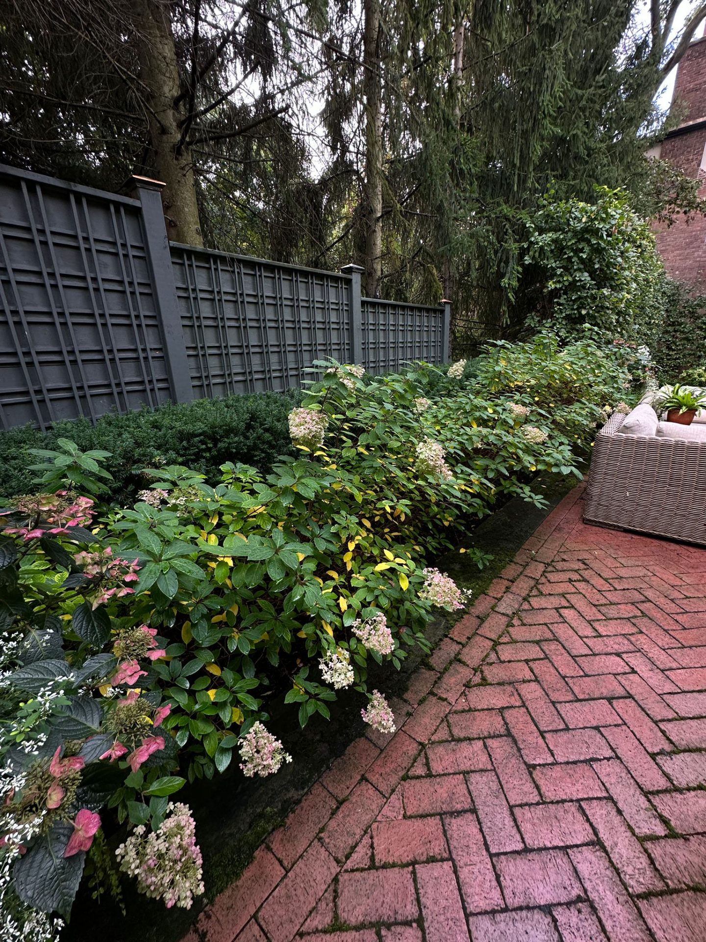 Garden with brick path and flowering bushes.