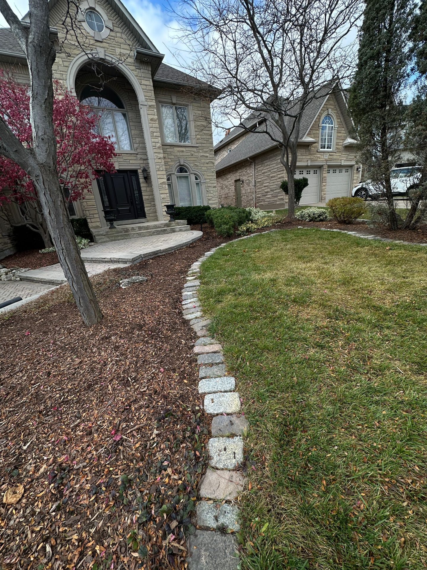 Stone house front yard with pathway and trees.