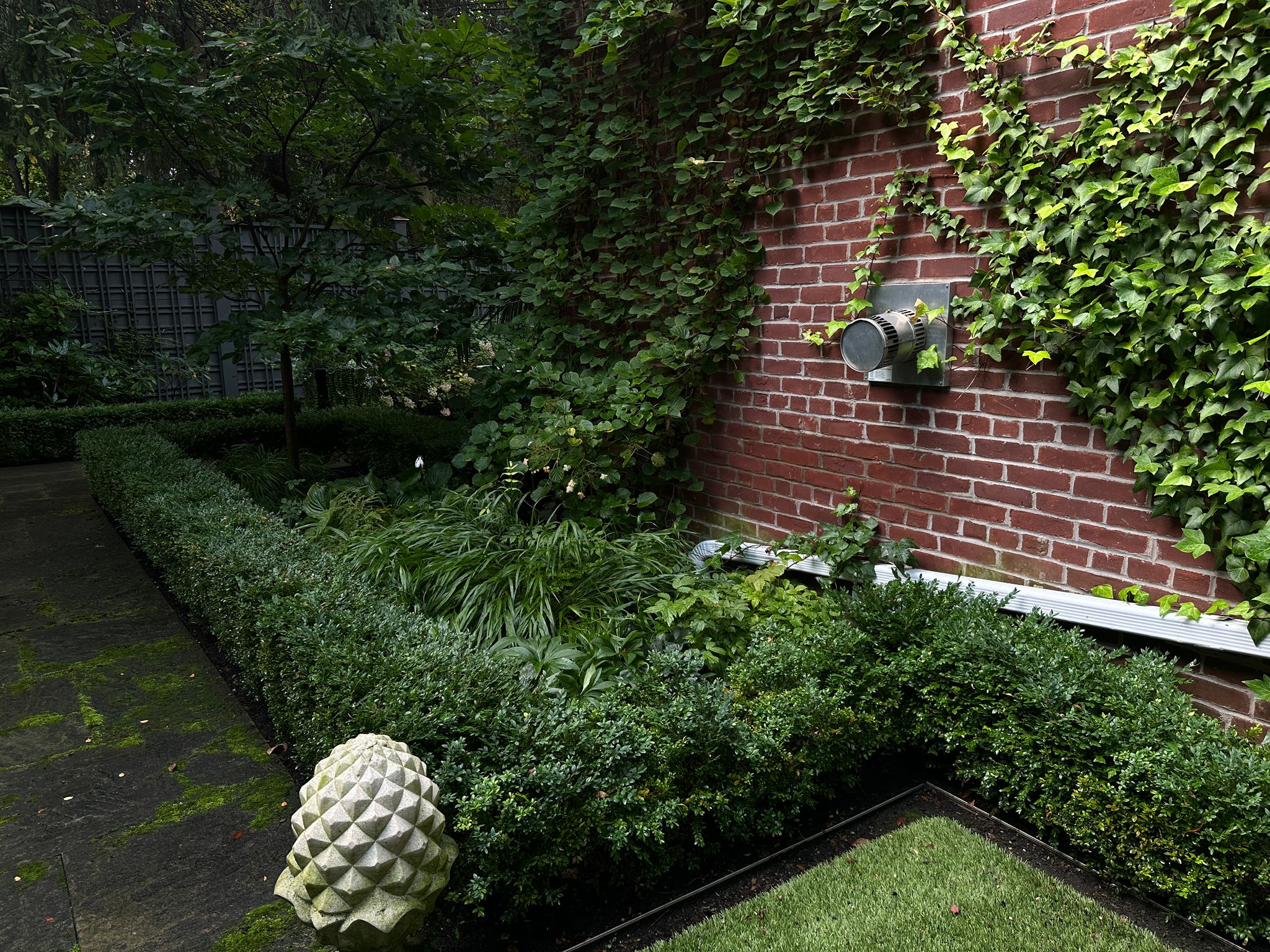 Brick wall with lush green garden and vines.