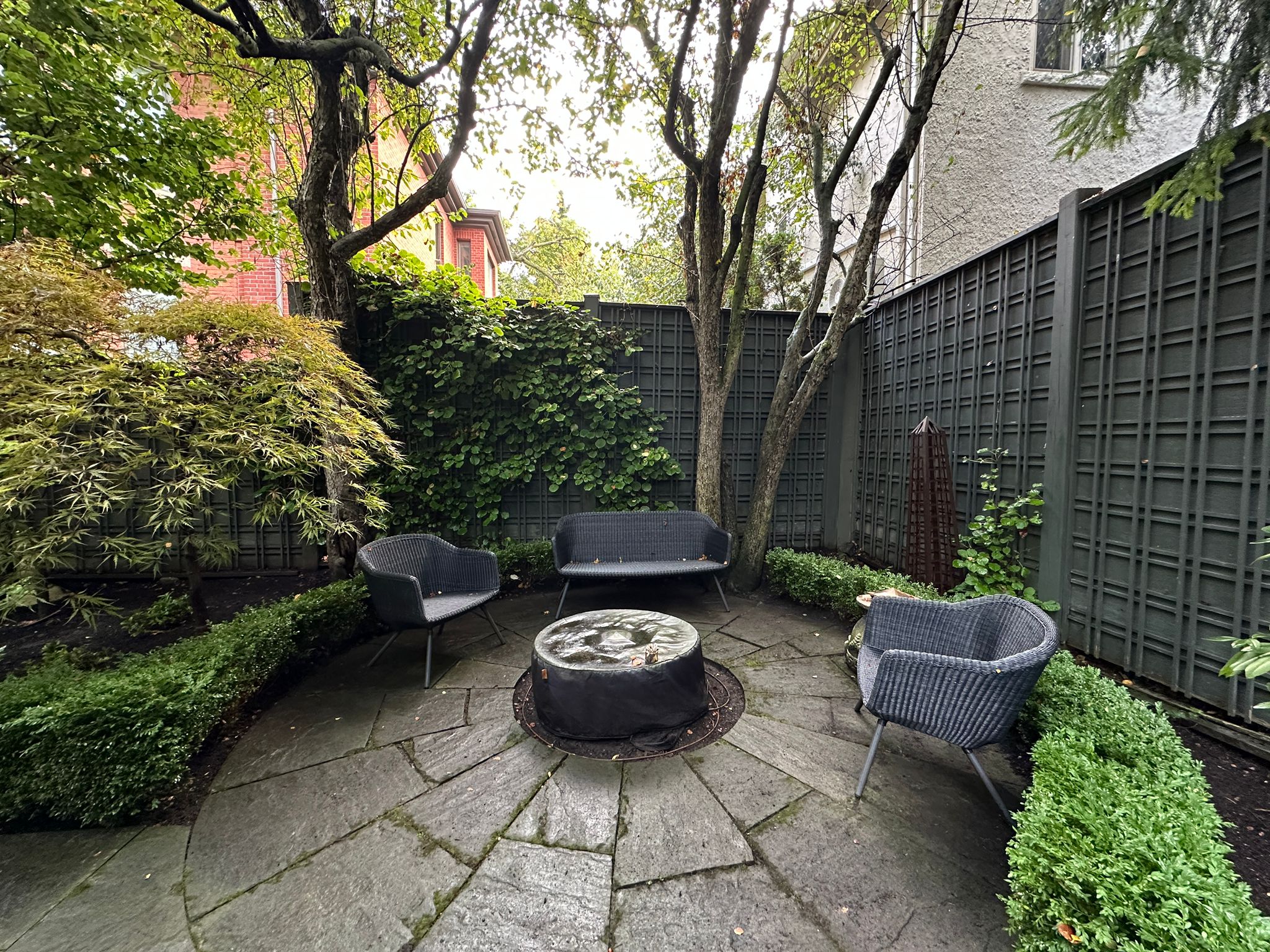 Cozy garden patio with chairs and trees.