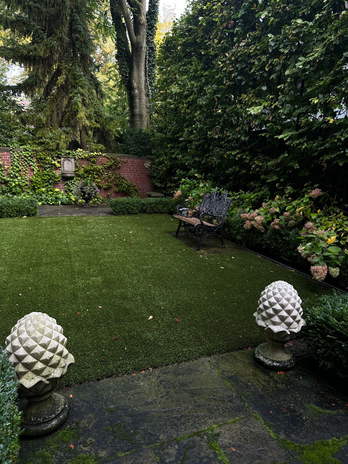 Peaceful garden with bench and brick wall backdrop.