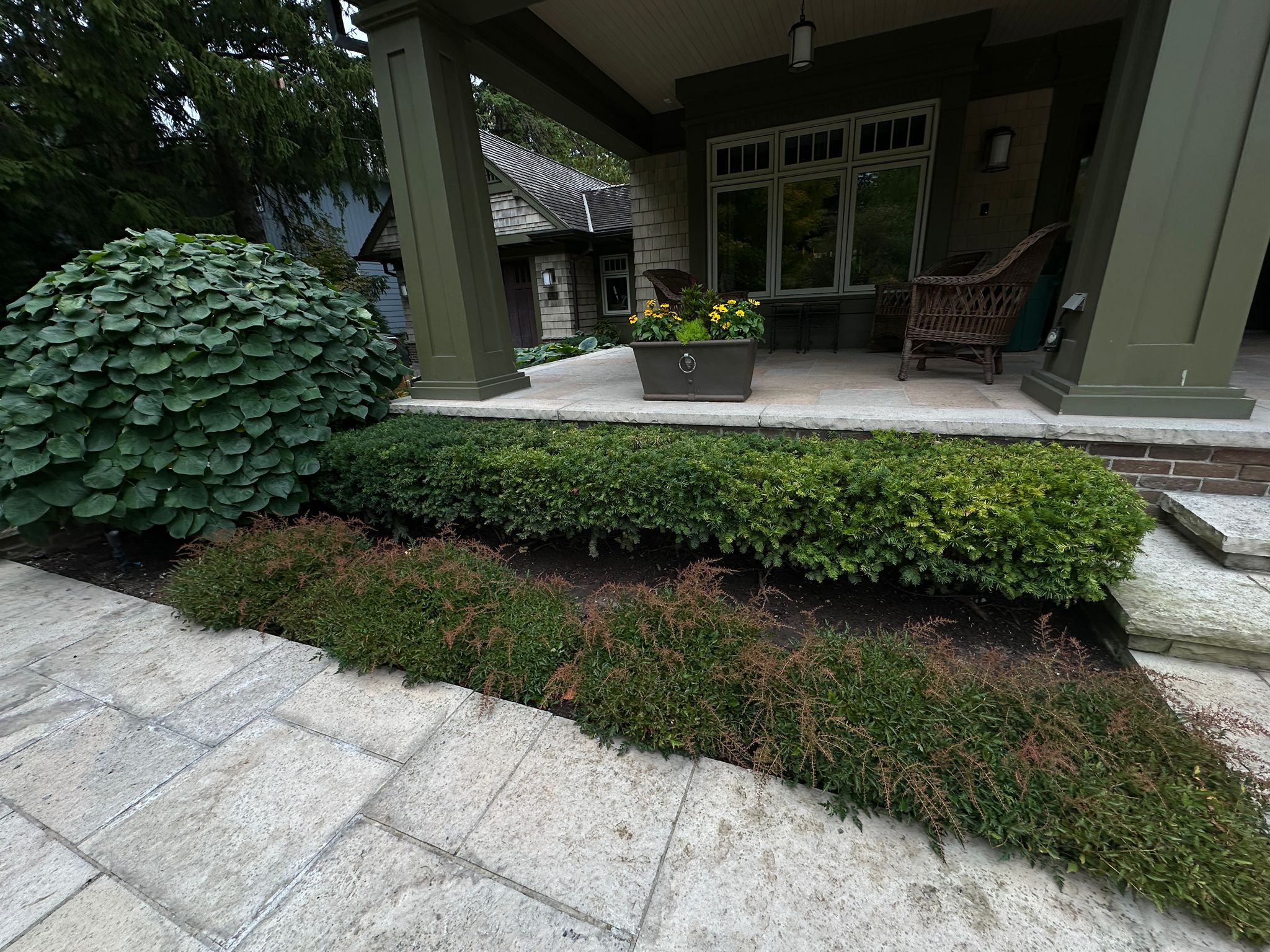 Front porch with lush greenery and seating area.