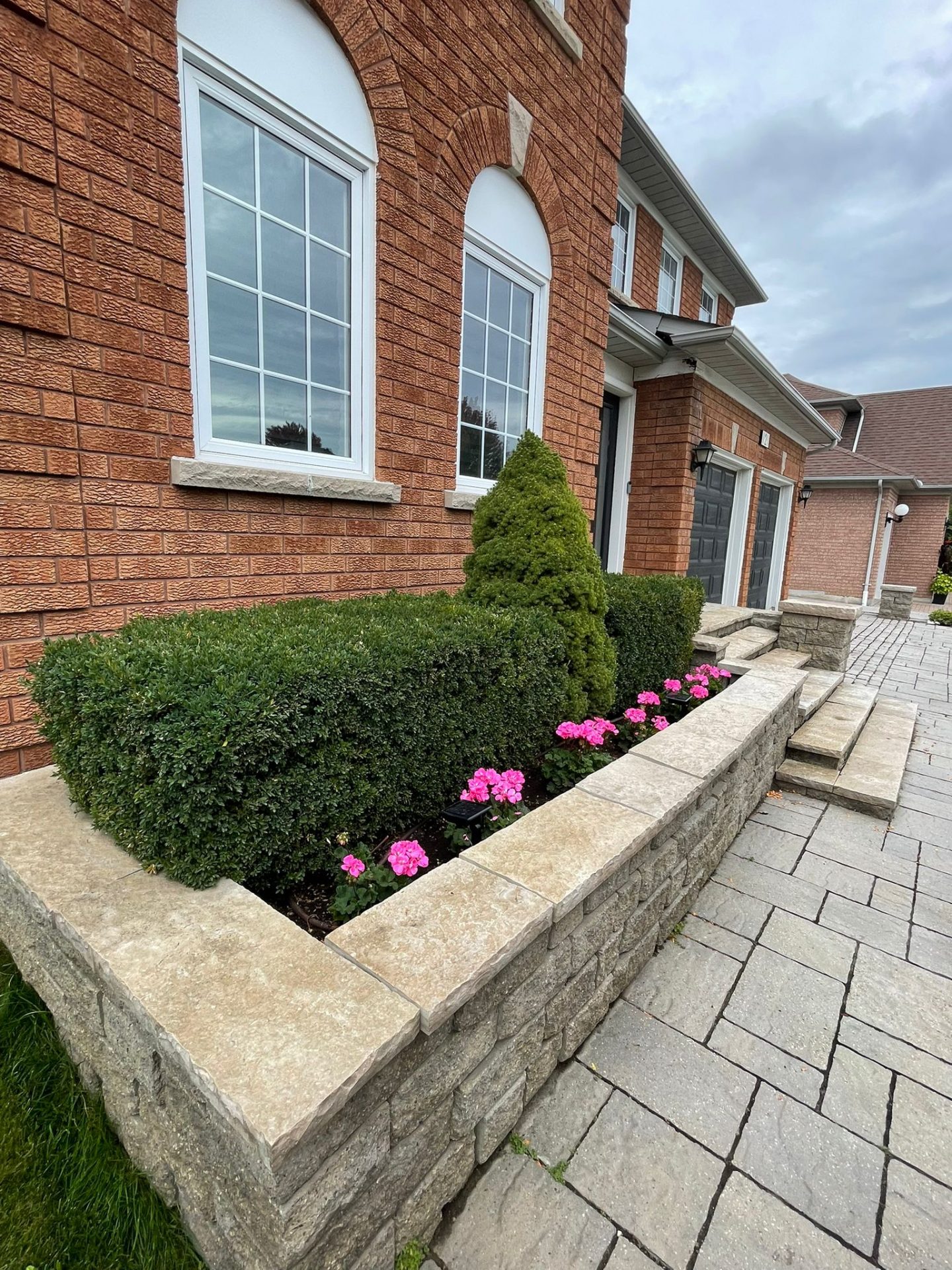 Brick house with hedges and pink flowers