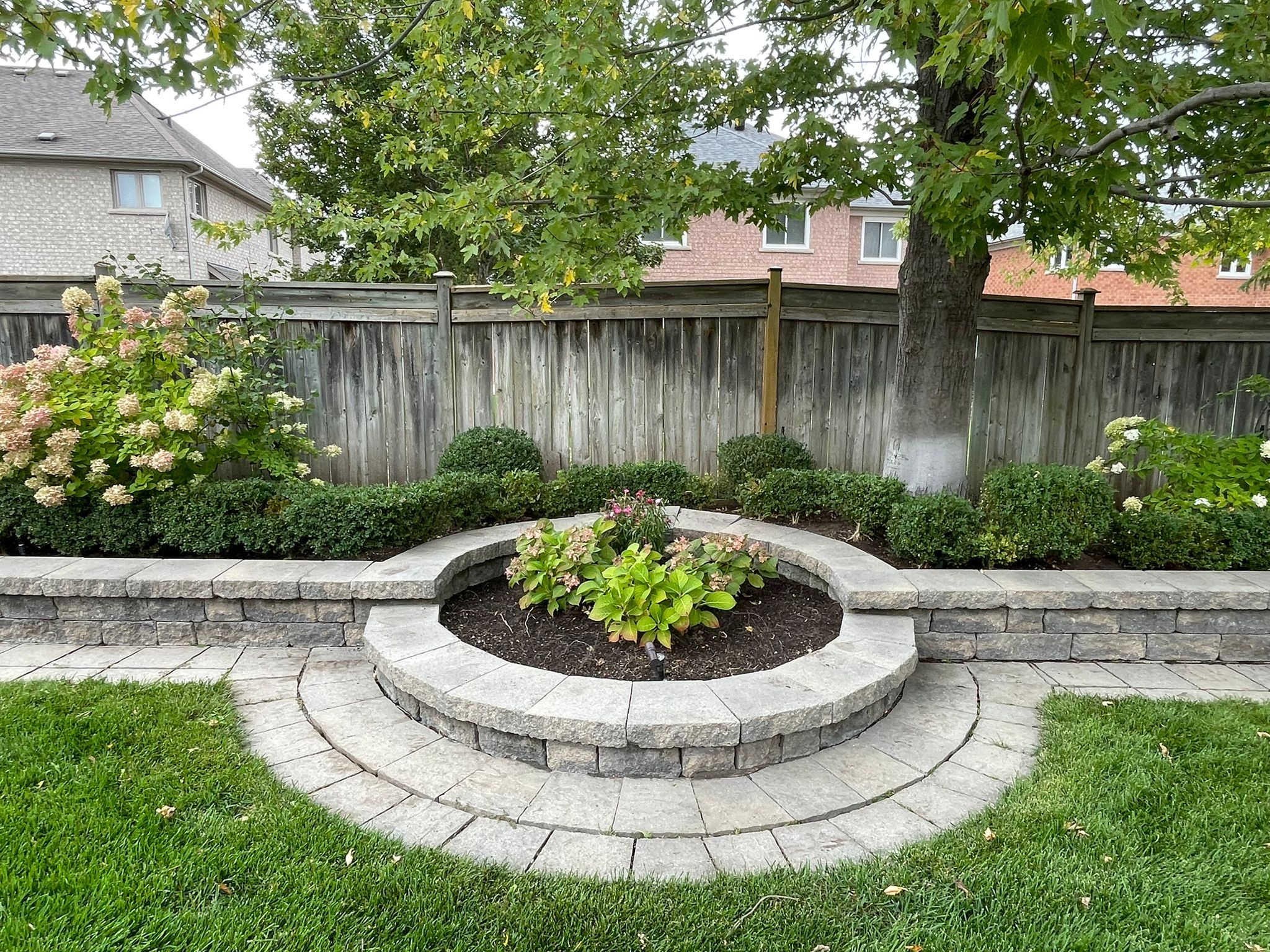 Stone garden with flowers and tree in yard.