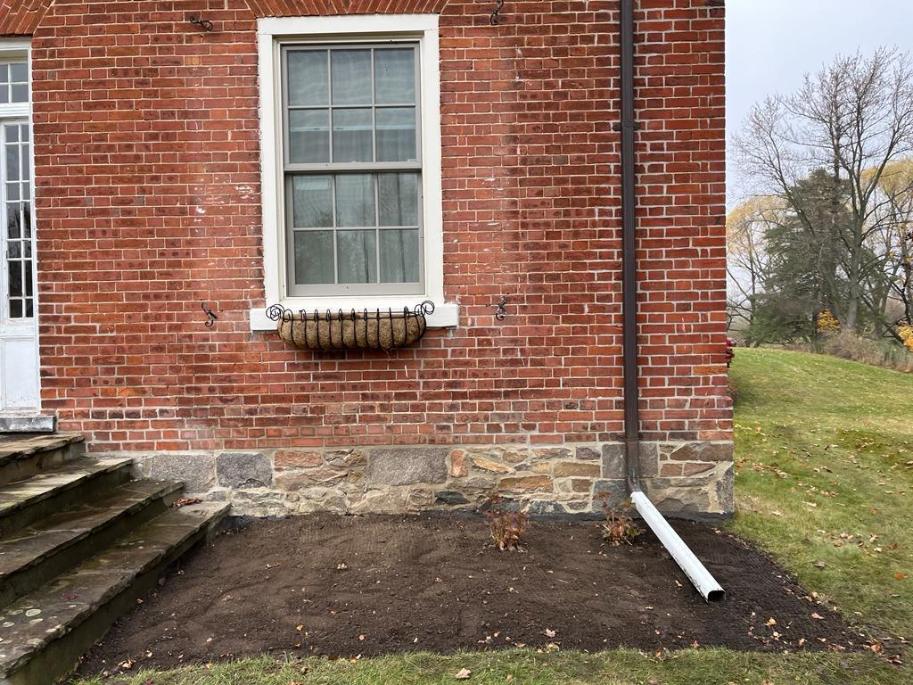 Brick wall with window and drainpipe on house.