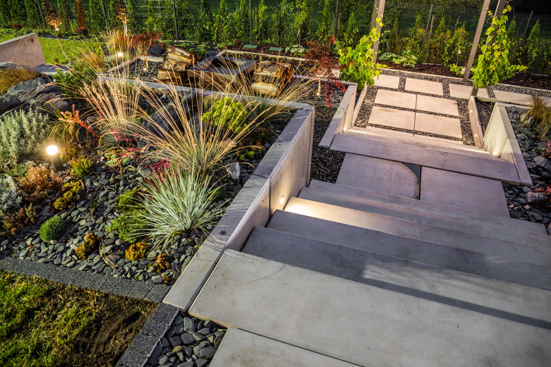 Modern garden with stone pathway and plants at night.