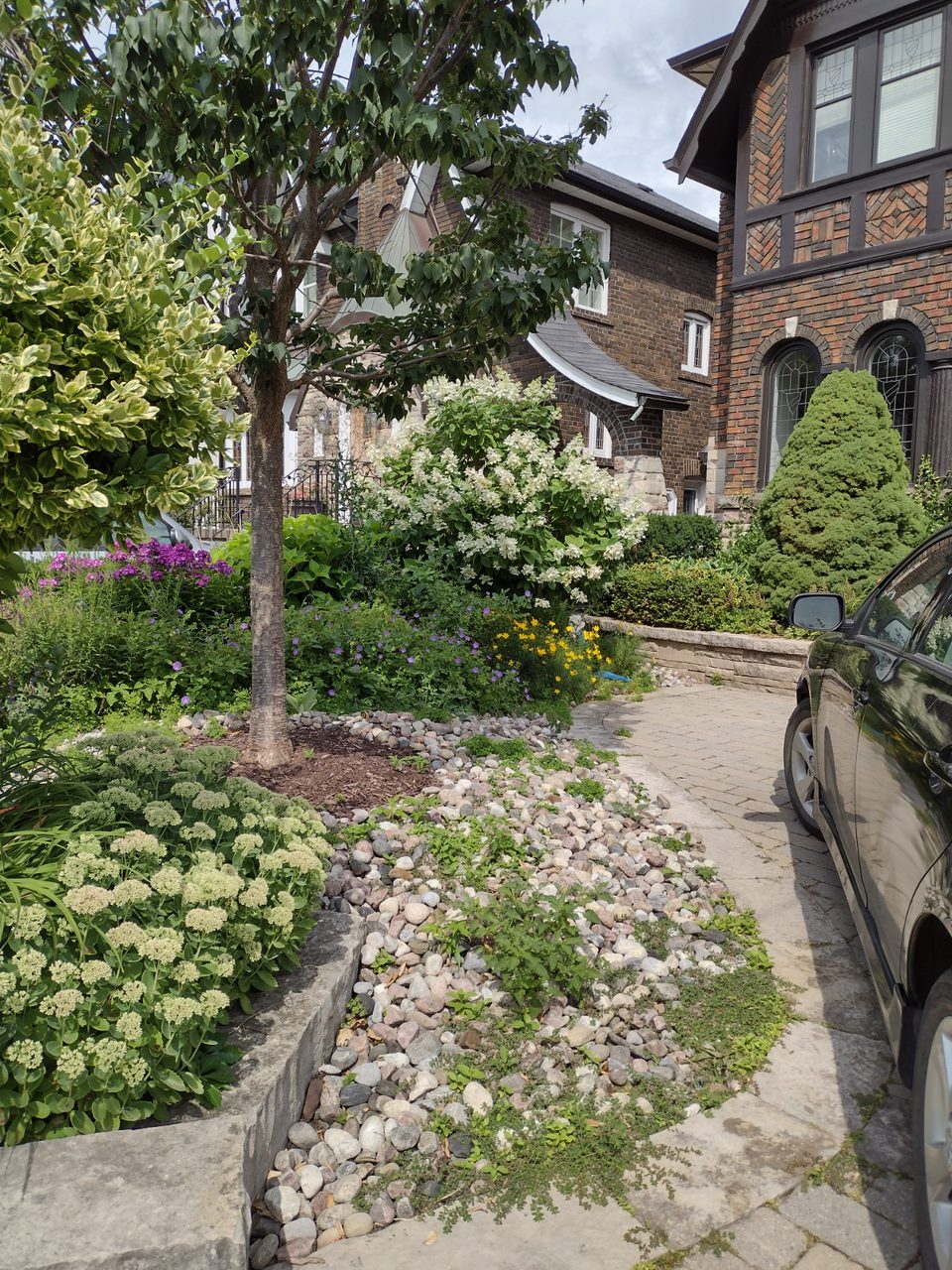 Brick house with lush garden and driveway.