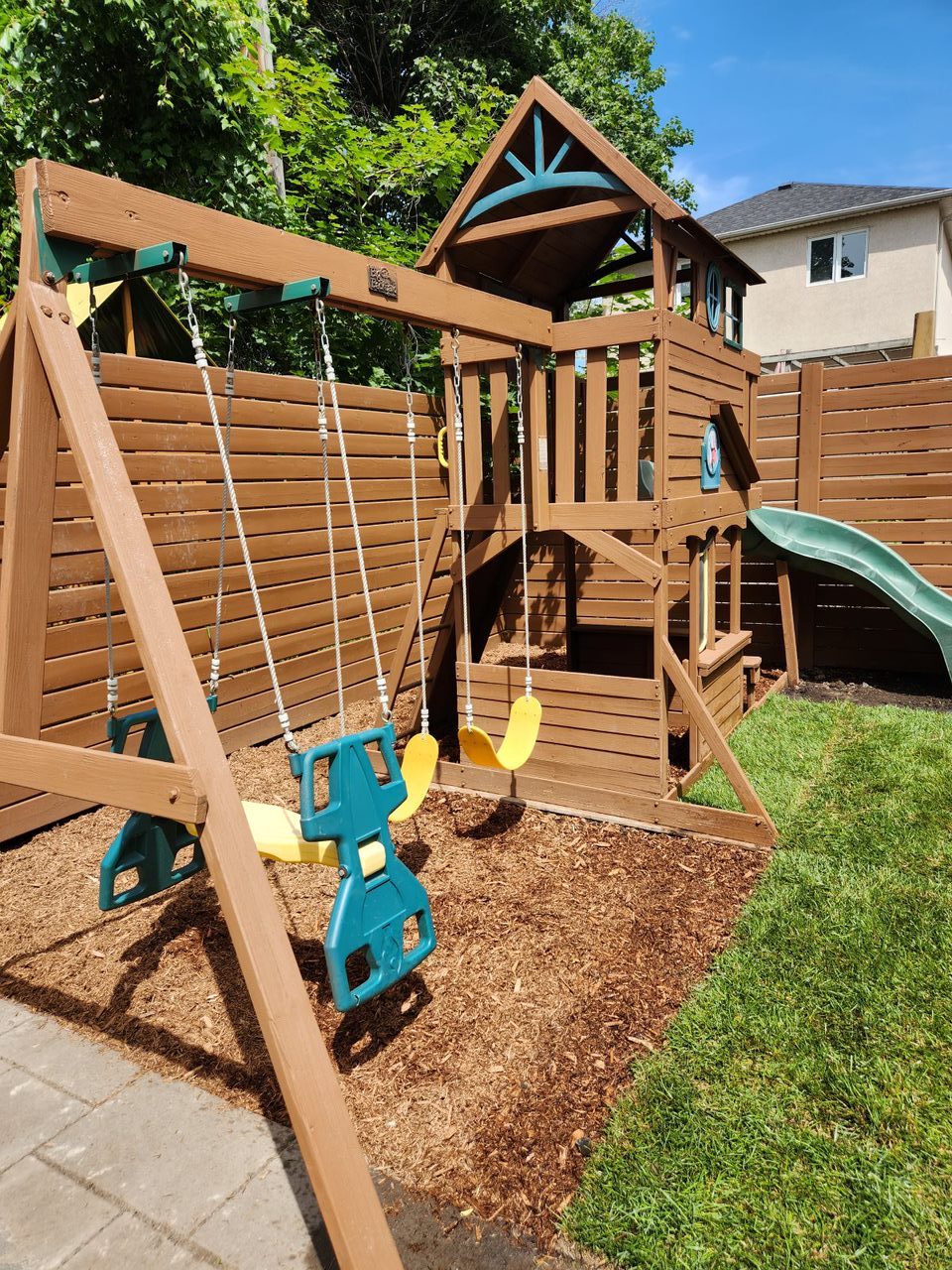 Wooden swing set with slide in backyard.